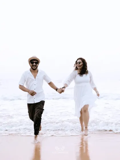 A joyful shot of the couple running hand-in-hand out of the ocean waves.