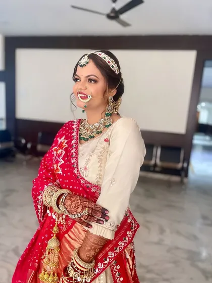 A stunning Marwadi bride in a traditional red and white bandhani saree. The makeup is bold and beautiful, with a focus on the eyes.