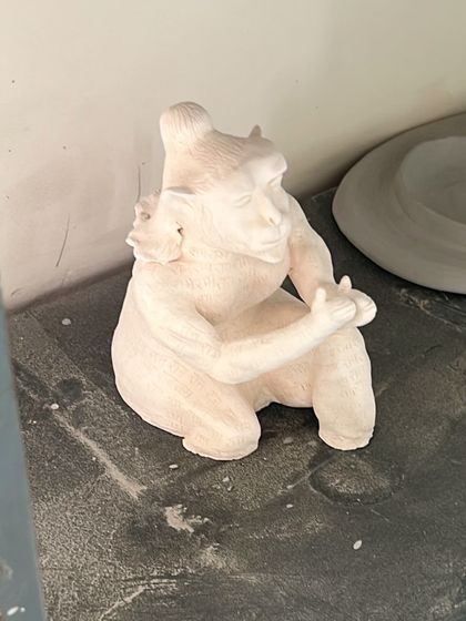 The Hanuman sculpture after its first firing (bisque firing). At this stage, the clay has turned white and is hard but still porous, ready for glazing or final touches.