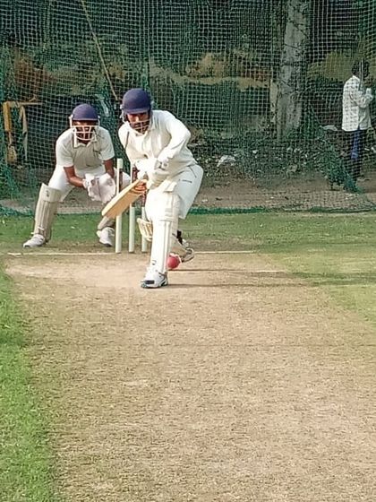 A batsman is captured mid-shot, connecting with the ball during a focused net session. Repetition and expert feedback are key to developing batting consistency.