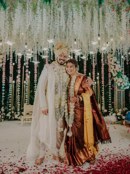 A grand portrait of the newly married couple on stage, under a stunning floral canopy. Their happy smiles show the joy of starting their new life together.