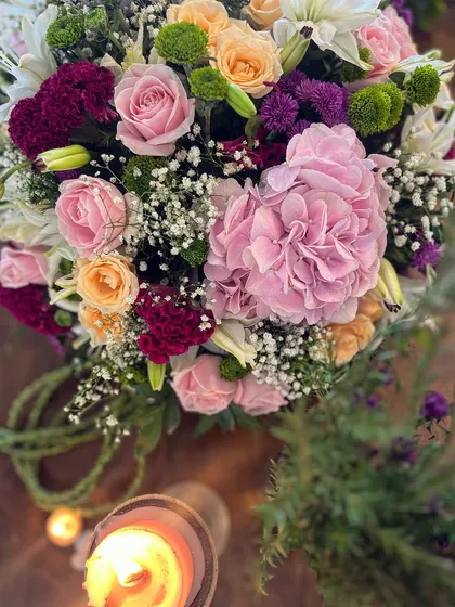 An overhead shot of a stunning floral centerpiece. The rich colors of the pink hydrangeas and deep red roses, illuminated by candlelight, showcase my passion for creating beautiful, atmospheric arrangements.