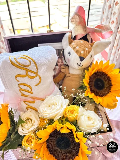 Another angle of the 'Raha' hamper, showing the arrangement of the personalized towel, plush toy, and fresh sunflowers in a pink keepsake box.