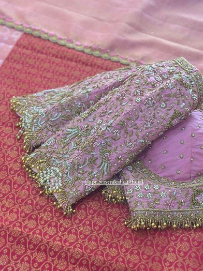 The sleeves of the pink blouse are heavily embroidered with floral motifs.