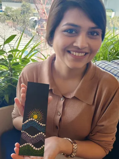 Even a brief art session can be a powerful moment of calm in a busy workday. This employee from Colliers is showing the dot art bookmark she made. Her smile reflects the quiet satisfaction of creating something beautiful with her own hands.