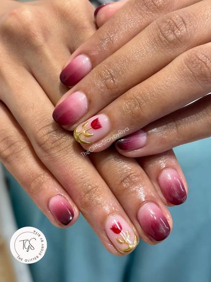 A romantic and elegant design featuring a deep red ombre effect. The accent nails have a delicate, hand-painted tulip with a gold stem, adding a touch of bespoke artistry.