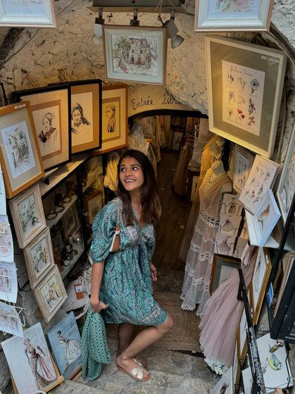 Exploring a quaint art shop in Eze. The whimsical setting and my flowy dress create a moment that feels like it's straight out of a storybook.