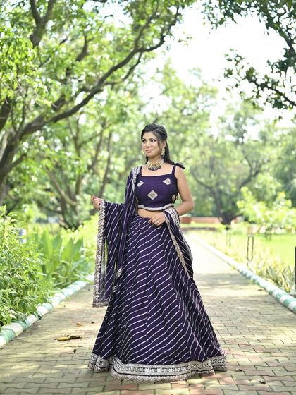 A deep purple lehenga featuring elegant silver leheriya stripes. This outfit combines a classic pattern with a rich color, making it a sophisticated choice for any festive occasion.