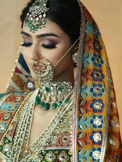 A close-up of a bride with a colourful, embroidered dupatta. The makeup features a subtle purple smokey eye to pick up the colours in her outfit.
