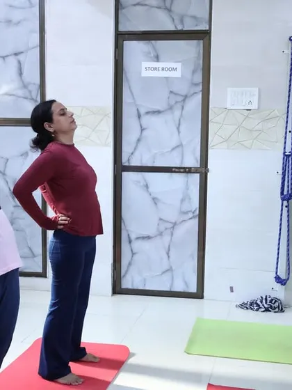 A group of women practices Ardha Chakrasana (Half Wheel Pose) in our studio. This standing backbend helps to improve posture, open the chest, and increase lung capacity.