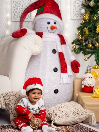 This baby boy in a festive reindeer sweater looks absolutely adorable as he sits among the Christmas presents.