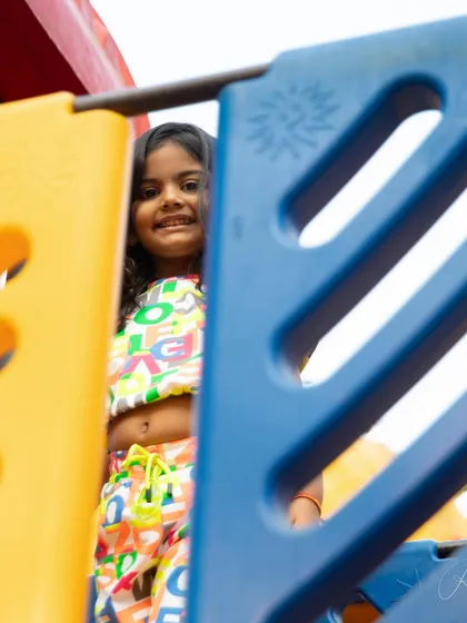 Peeking through the playground equipment with a smile. These playful, hide-and-seek moments make for such fun and natural photographs.