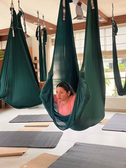 A student finds a moment of rest and contemplation inside the aerial silk cocoon. This gentle pose is perfect for relaxation and releasing tension at the end of a class.