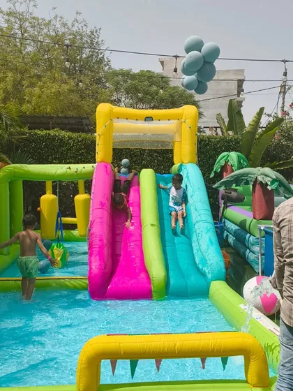 Two friends racing down the double-lane inflatable water slide into the pool below.