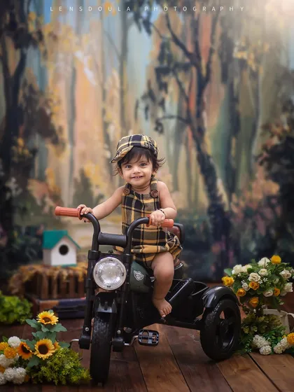Ready to ride through the woods! This little adventurer looks right at home in our forest-themed setup, complete with a cool tricycle and a charming plaid outfit.