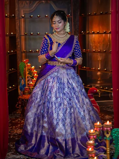 A graceful pose showing the flow of the half-saree. The makeup and hairstyle are traditional, perfect for a cultural event.