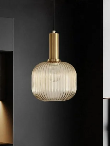 Here is the Cordelia pendant in a cylindrical shape, shown in a modern kitchen setting. Its warm, ribbed glass and simple form provide both functional light and a touch of sophisticated design.
