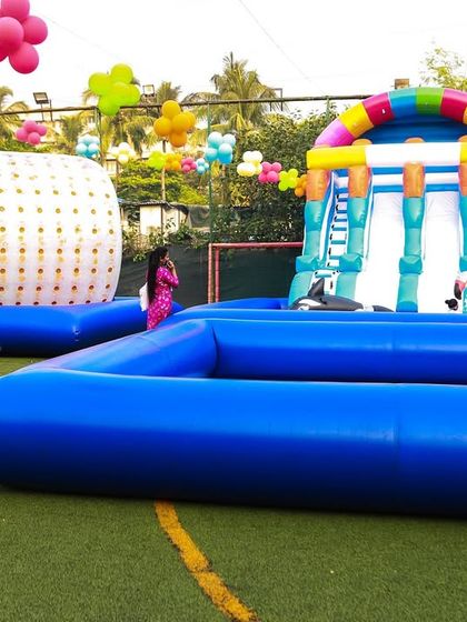 A large-scale pool setup featuring a water zorbing ball and a tall inflatable slide, demonstrating the variety of high-energy water activities I can arrange.