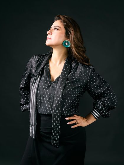 Kajol looking powerful and chic in a black printed blouse and skirt, with statement turquoise earrings adding a bold splash of color.