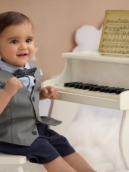 A dapper little gentleman at the piano. We have a wide selection of formal wear to create elegant and classic milestone portraits.