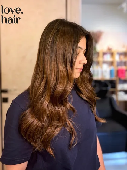 A profile shot of the pure hazelnut balayage, styled in soft waves to show off the beautiful, warm tones.