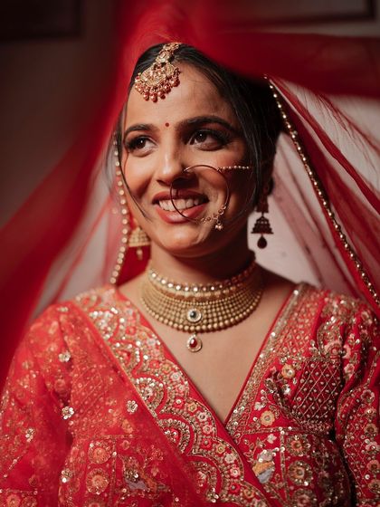 A close-up of the bride smiling, her face framed by her red veil. This shot captures her pure joy and the vibrant colors of her wedding attire.