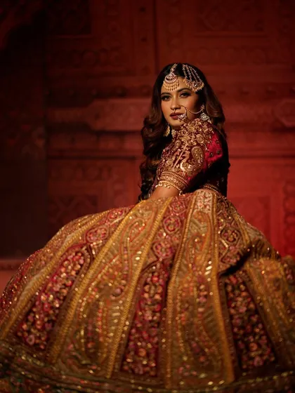 A royal and dramatic bridal portrait inspired by Heeramandi. The bride is wearing a heavy red and gold lehenga, and her makeup is bold and captivating.