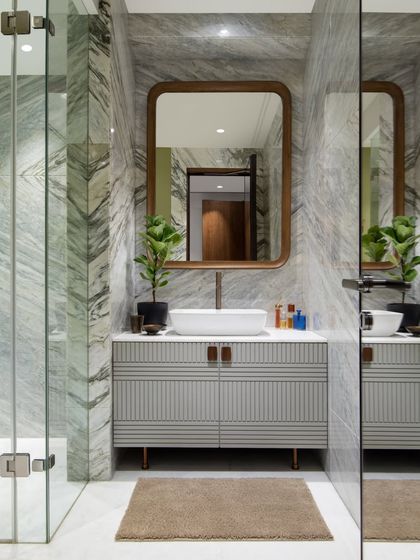 This bathroom showcases our love for material layering. The walls are clad in a striking green and grey marble, paired with a custom fluted vanity from our Koko collection. The wood-framed mirror adds warmth, creating a space that is both bold and balanced.
