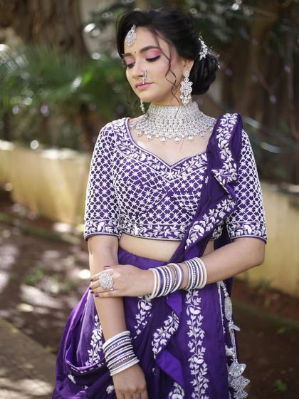 A serene portrait in the purple and white lehenga. The detailed embroidery on the blouse and the matching bangles create a cohesive and beautiful look.