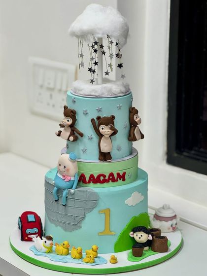 This multi-tiered first birthday cake creates a magical world of adventure. It features hand-crafted monkeys, fluffy clouds, and tiny ducks, with countless details to discover on every level.