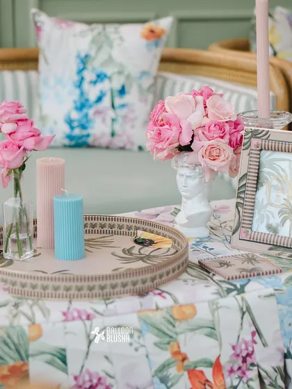 A close-up of a tray with pastel-colored candles, a small bust-shaped vase, and a framed picture, showing the attention to small details.