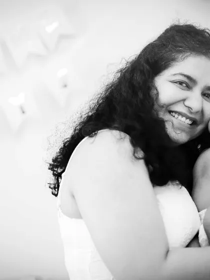 A smiling mother holding her newborn baby. The black and white edit brings out the pure joy and love in her expression.