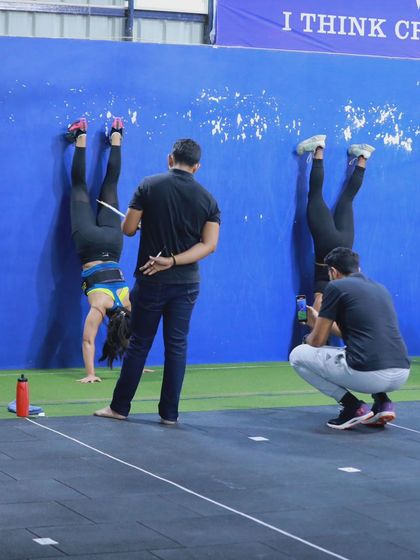 Judging the standards. A judge watches closely as athletes perform wall walks, ensuring every rep meets the required criteria for a fair competition.