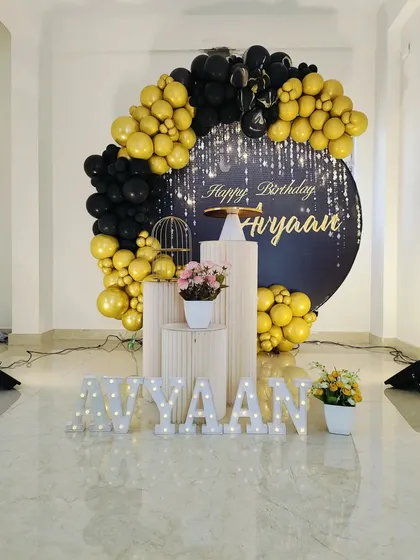 Our services extend to sophisticated and chic celebrations for adults. This stylish black and gold themed birthday setup includes a custom backdrop with a sparkling design, a matching balloon garland, illuminated marquee letters for the name, and clean, modern pedestals.