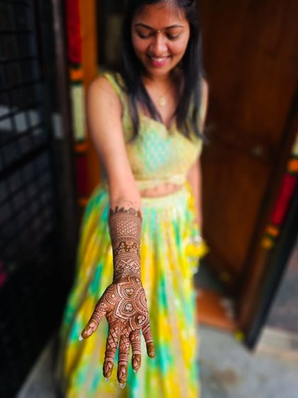 A happy bride presenting her beautiful henna, a mix of traditional mandala and modern skyline art.