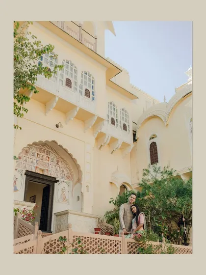 A wider shot of the couple on the palace balcony, showing more of the building's beautiful facade and creating a sense of place.