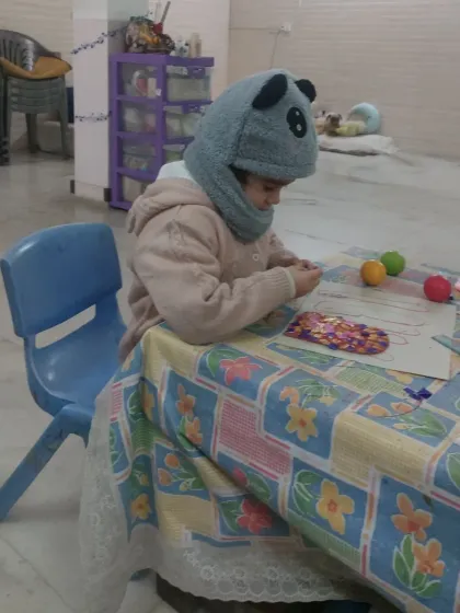 A preschooler deeply focused on her craft project. Our sessions are designed to hold the attention of even the youngest learners through engaging and age-appropriate activities.