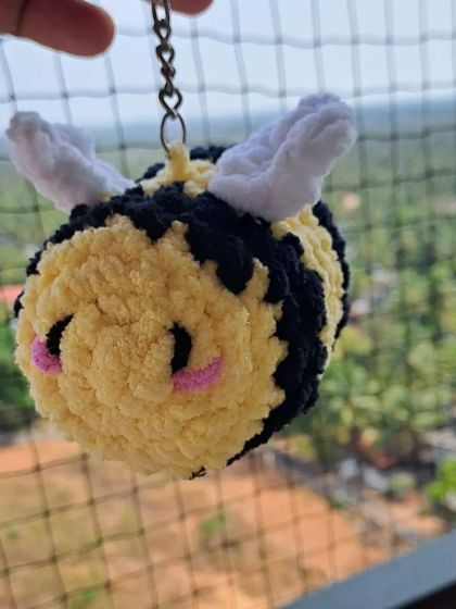 Another shot of the fluffy bee keychain, showing off its cute, chubby shape and soft texture from the plush yarn.