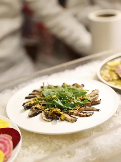 Sliced grilled mushrooms topped with fresh arugula and pistachios, served on a bed of ice to maintain its perfect temperature and freshness.