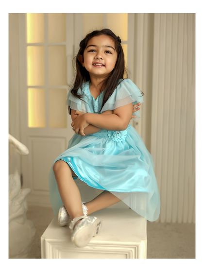 A sweet toddler portrait in a beautiful light blue dress. The simple, elegant studio setup with soft lighting creates a timeless and classic look.