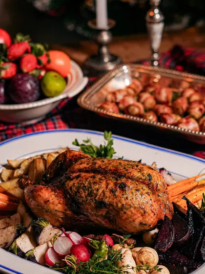 A whole roasted chicken served with roasted root vegetables. This is a comforting and classic main course, perfect for a family dinner or a small gathering.