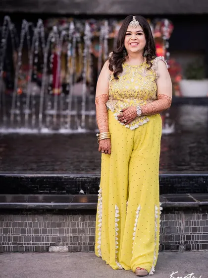 The client's full look for her Mehendi ceremony, with voluminous curls that are perfect for the happy occasion. The hairstyle is comfortable yet glamorous.