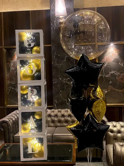 A chic birthday setup featuring a stack of customized balloon cubes spelling out a name. I paired it with a black and gold helium balloon bouquet for a coordinated look.