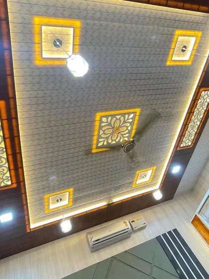 Sirf zameen hi nahi, hum chhat ko bhi aasmaan bana dete hain. Yeh ek PVC false ceiling ka design hai jismein custom light fittings aur jaali work kiya gaya hai. Isse poore kamre ki raunak badh jaati hai.