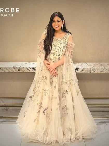 Simply enchanting. This off-white gown with delicate floral embroidery and cape sleeves is a dreamy and elegant choice for any formal event.