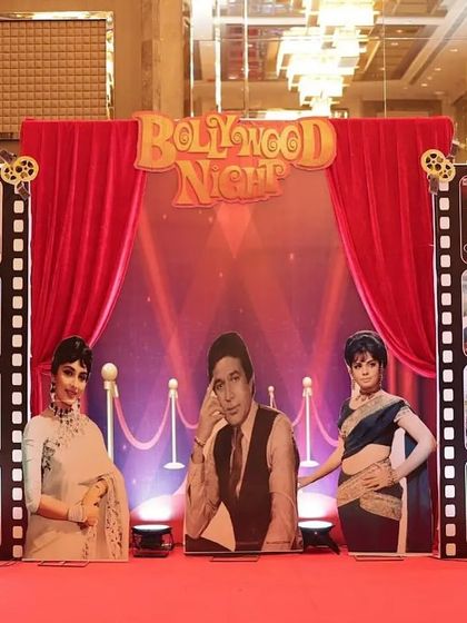 The stage is the heart of any event. This "Bollywood Night" setup featured a red carpet, classic film posters, and life-sized Oscar statues, creating a perfect backdrop for performances and announcements at a corporate awards night.