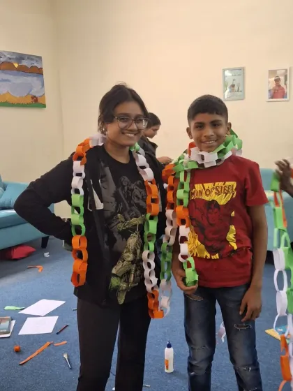 A volunteer and a child playfully wear the tri-color paper chains they made. These moments of shared fun and laughter are what make our celebrations so special.