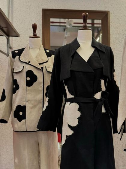 A closer look at the black and white collection, featuring a trench coat with floral cutouts and a jacket with bold flower prints.