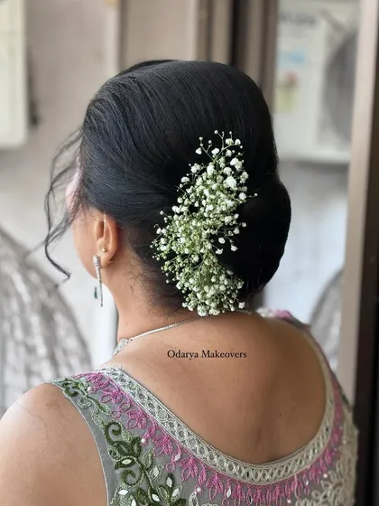 A simple and elegant bun for a wedding guest, adorned with baby's breath. This style is timeless and suits any traditional outfit.