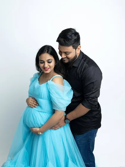 A close-up couple's portrait focusing on their connection. Both parents-to-be gently hold the baby bump, a classic pose that symbolizes their shared anticipation and joy.